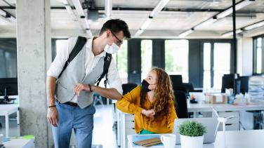 2 young people elbow bumping in the office